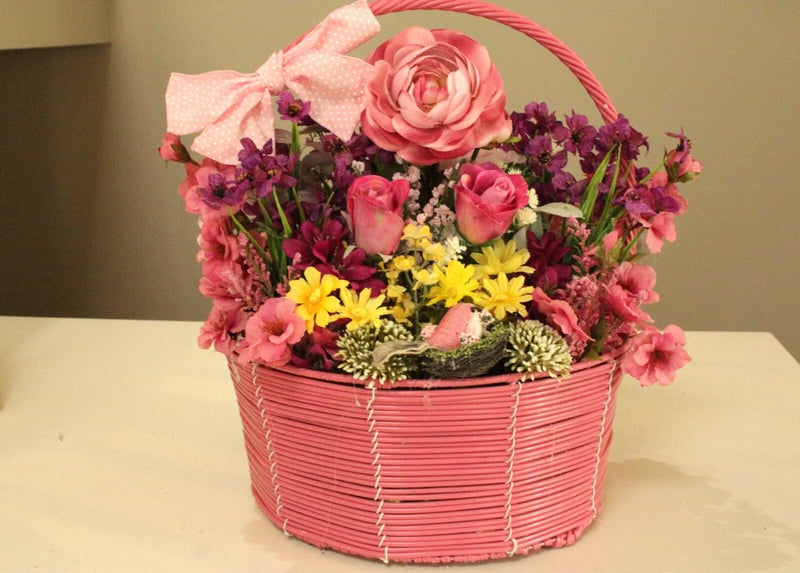 Pink wicker flower basket with sunflowers, roses, and purple blossoms
