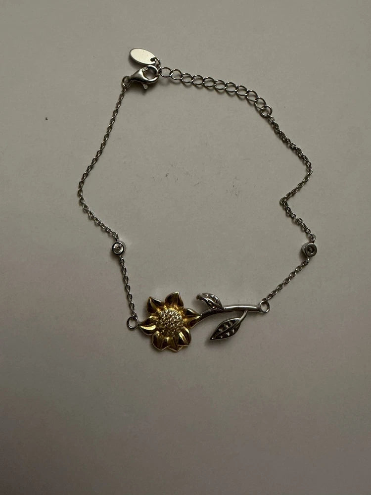 Silver-tone adjustable bracelet with gold sunflower charm and leaf-shaped charm