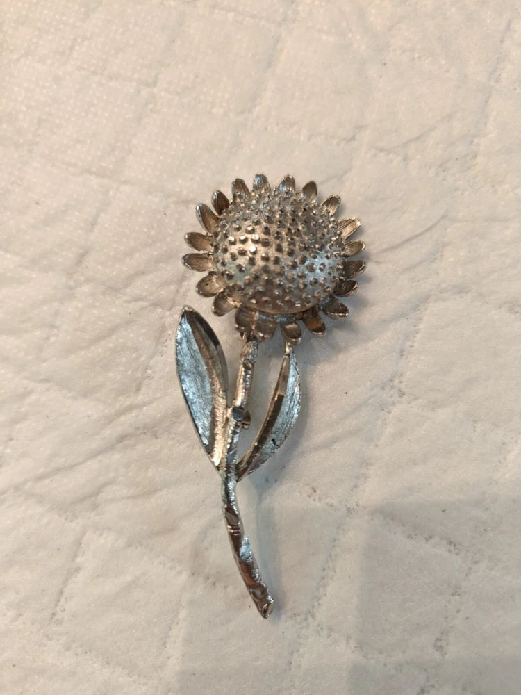 Silver-tone sunflower brooch with textured petals and metallic leaf accents