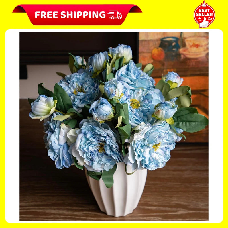 Large faux blue peony flower bouquet with green leaves and long stems in white vase