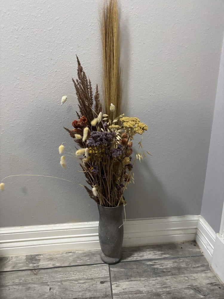Dried flower arrangement in gray vase with brown, yellow, purple, and cream stems