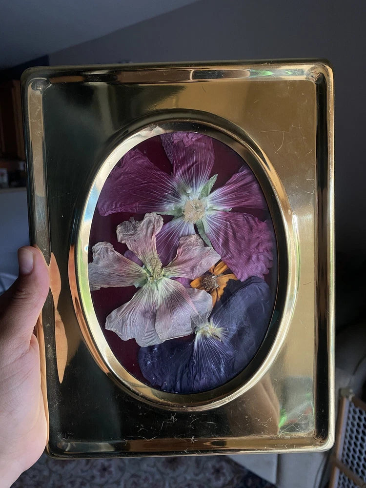 Oval framed pressed dried flowers in gold frame with purple and white blooms