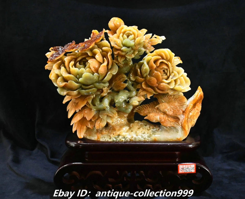Carved jade-style statue with peony flowers and bird perched on dark base