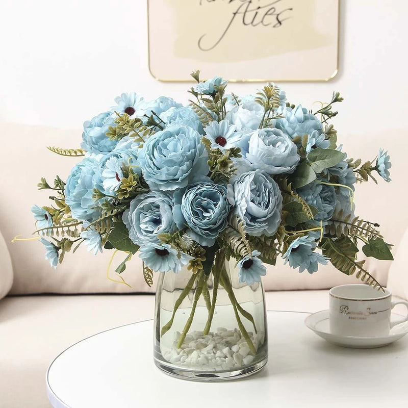 Artificial light blue peony rose floral bouquet in clear glass vase, with green leaves