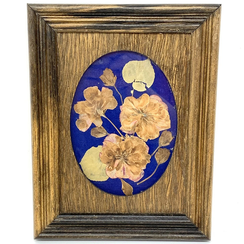 Reclaimed wood framed wall hanging with pressed flowers on blue oval background