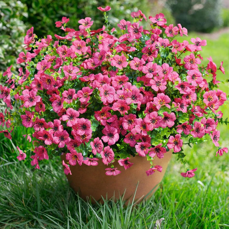 Artificial pink flower plant with green leaves in a small pot