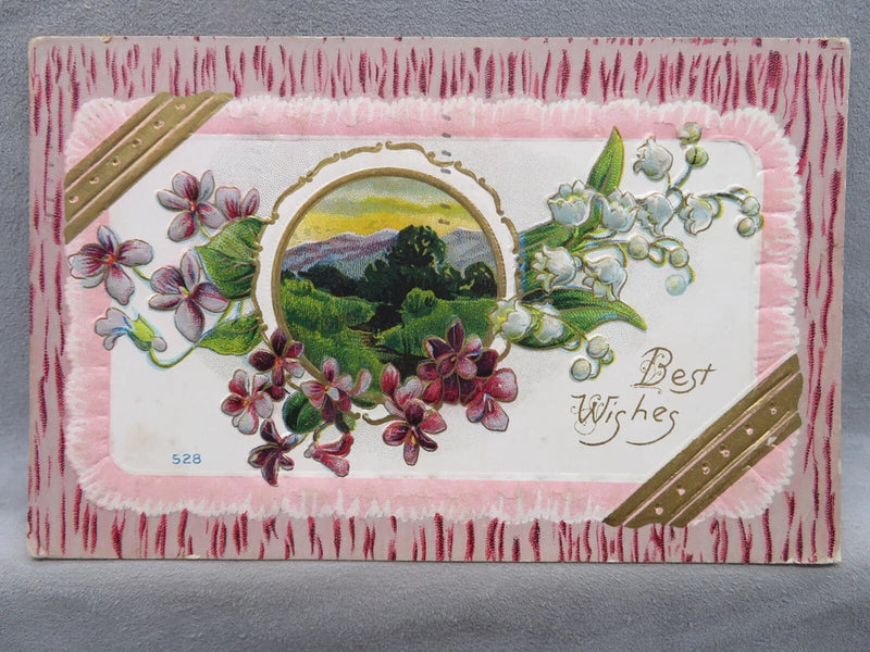 Pink embossed floral postcard with landscape scene and 'Best Wishes' text