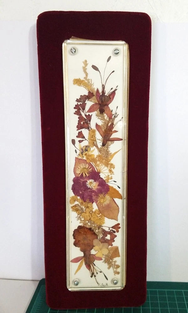 Vertical framed dried flower wall art panel with maroon backing and pressed floral arrangement