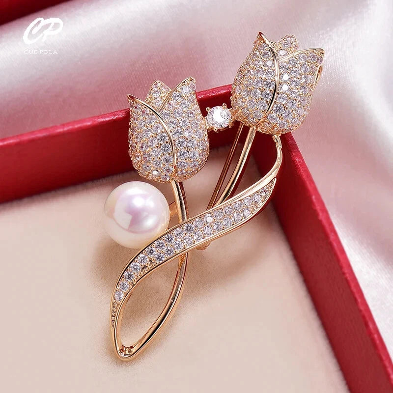 Gold-tone floral brooch with rose-like petals, crystal shimmer and white pearl drop