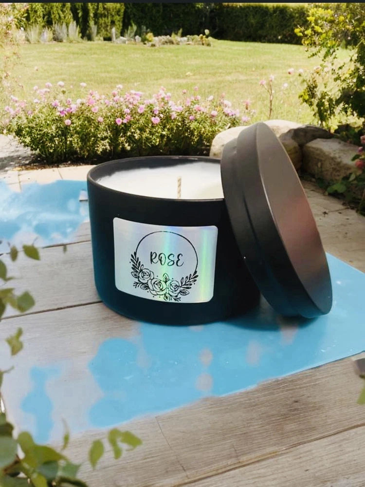 Rose-scented candle in dark glass jar with white wax and lid, floral rose label