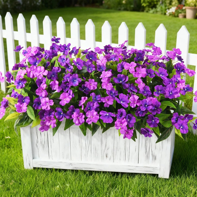 Artificial impatiens flowers with purple blossoms in a white wooden planter box
