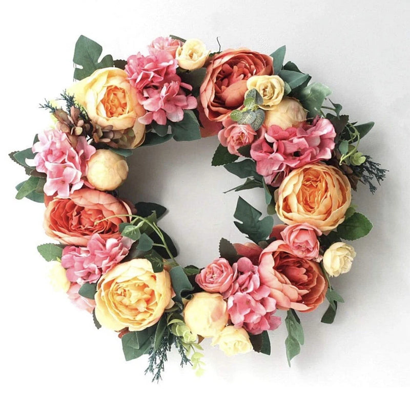 Artificial peony flower wreath with pink, orange, and cream blooms and green leaves
