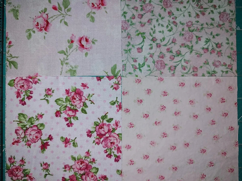 Quilting fabric squares set with tiny pink roses on light pink base