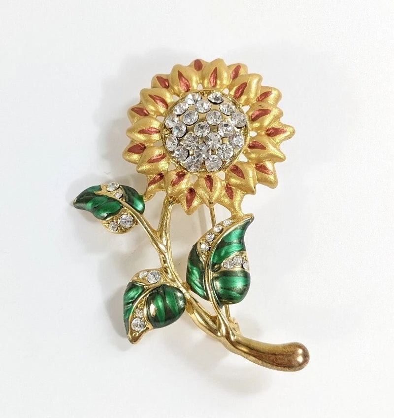Gold-tone sunflower rhinestone brooch pin with green leaf accents and circular crystal center