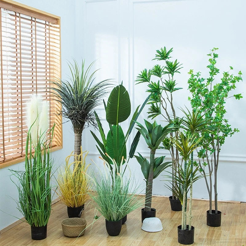 Set of artificial potted plants with tall green grass and leafy stems in black pots