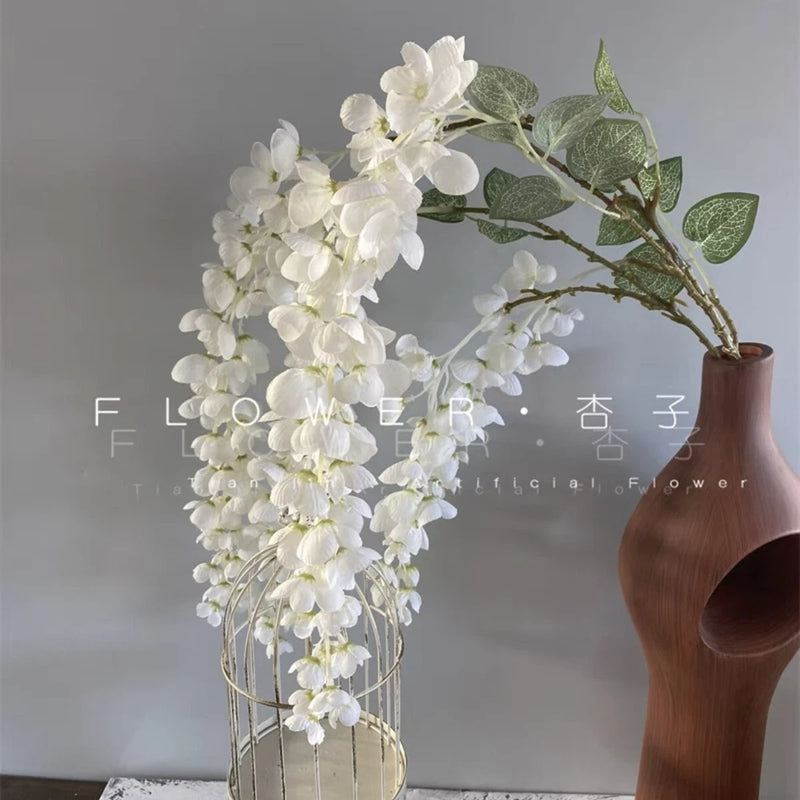 Faux white flower arrangement with cascading blossoms in brown vase