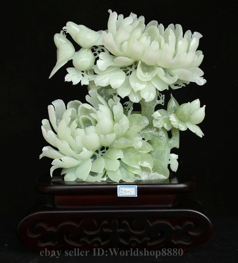 Carved jade flower-and-bird sculpture with peony blossoms on dark wooden base
