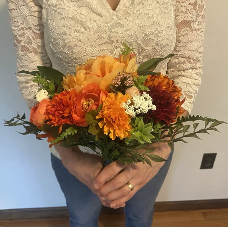 Handmade faux bridal bouquet with orange, yellow, and red flowers and green foliage