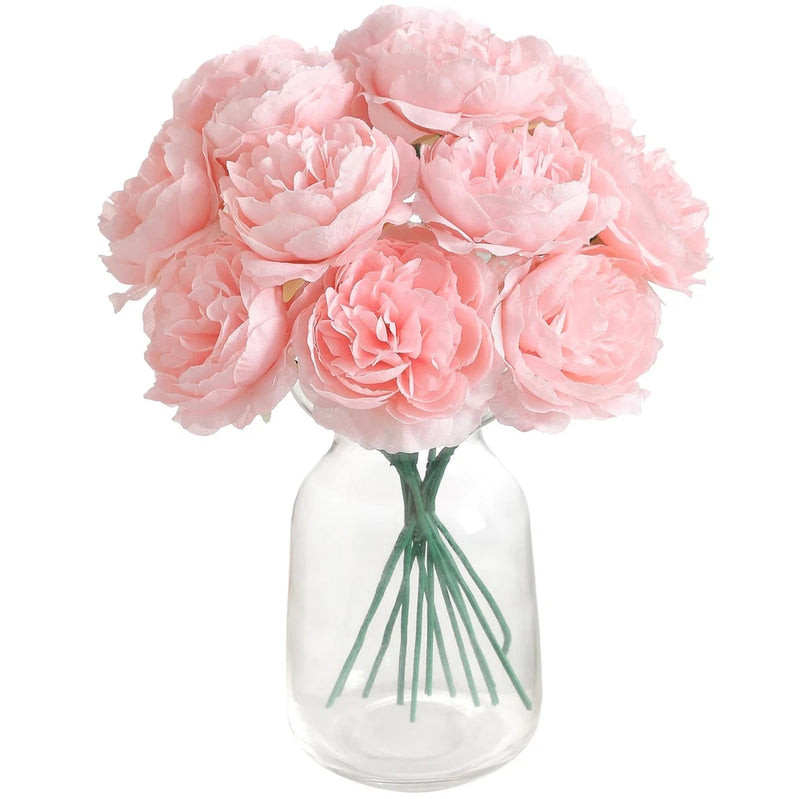 Artificial silk peony flower bouquet in pink with green stems in a clear glass vase