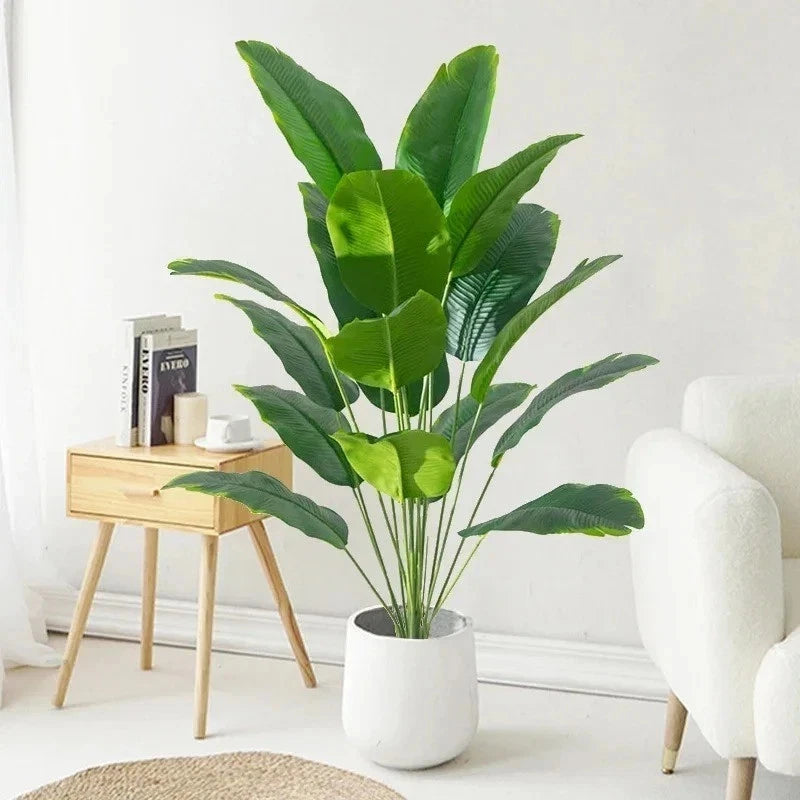 Large artificial tropical palm tree plant in white pot with broad green leaves