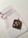 Pressed flower lily pendant with square resin bezel and dark metal loop bail