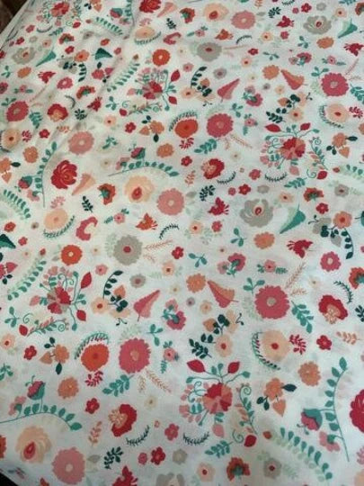 Cotton fabric with scattered carnation-style floral print in red, pink, and green