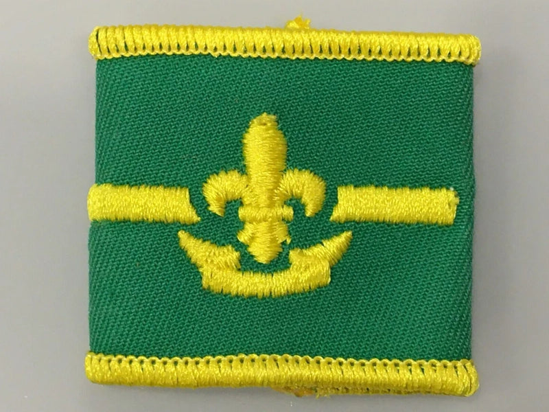 Green fabric shoulder patch with yellow fleur-de-lis flower emblem and rope border