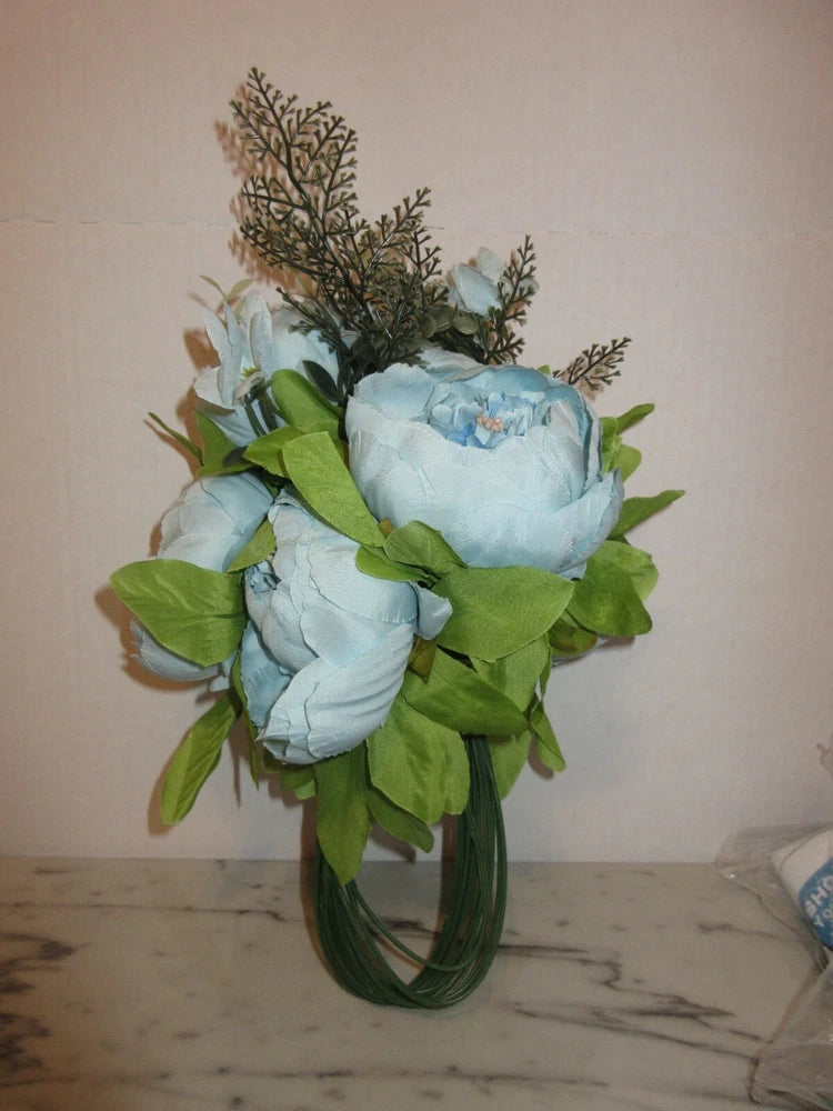 Artificial peony silk flower bouquet with blue blooms and green leaves in a vase