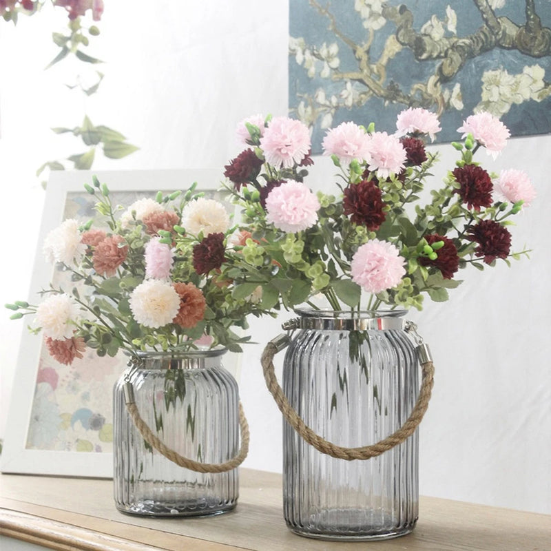 Artificial lilac-style flower arrangement with green leaves in two glass vases