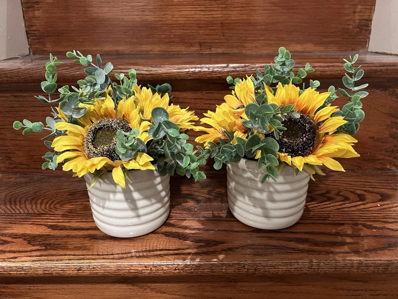 Pair of artificial sunflower arrangements with yellow blooms in white striped planters