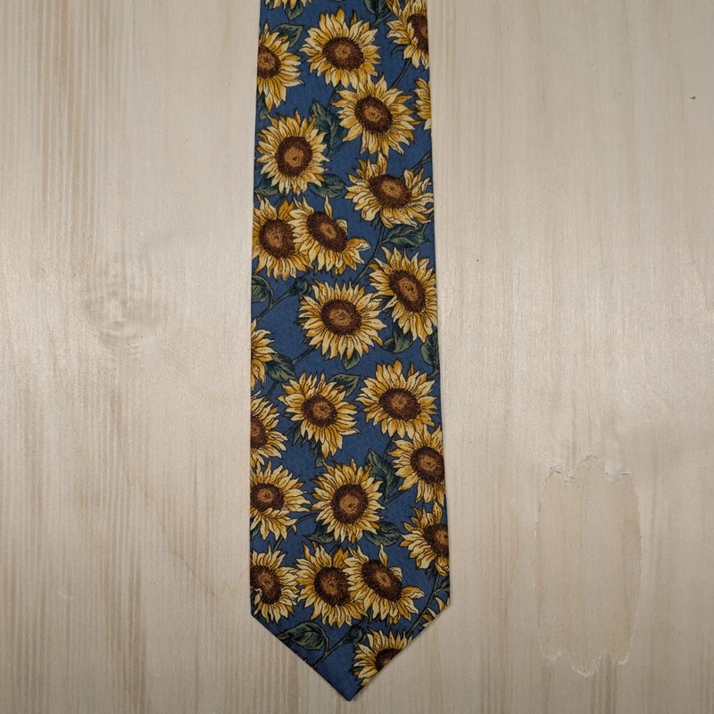 Navy necktie with repeating sunflower pattern, slim design with pointed tip