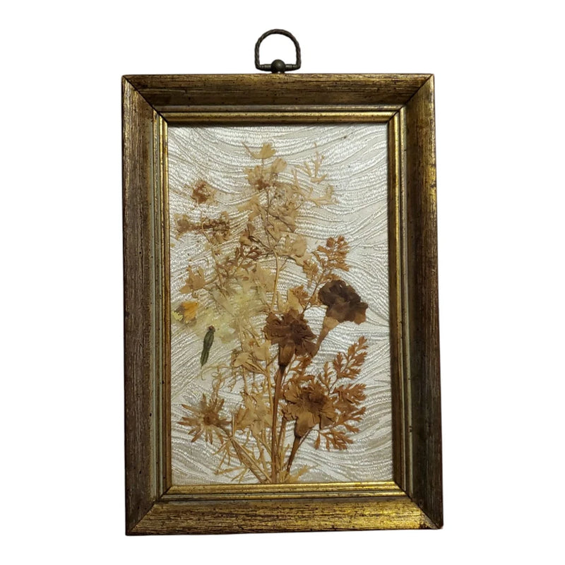 Wood-framed pressed dried flowers wall art with tan blooms on light fabric background