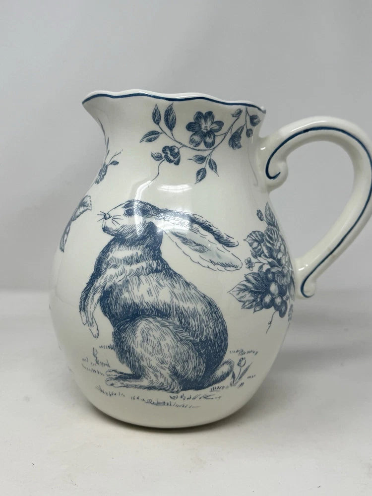 Blue and white ceramic pitcher with rabbit-and-rose toile design