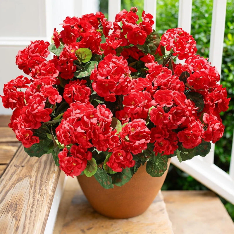 Artificial red geranium silk flowers with green leaves in a brown pot