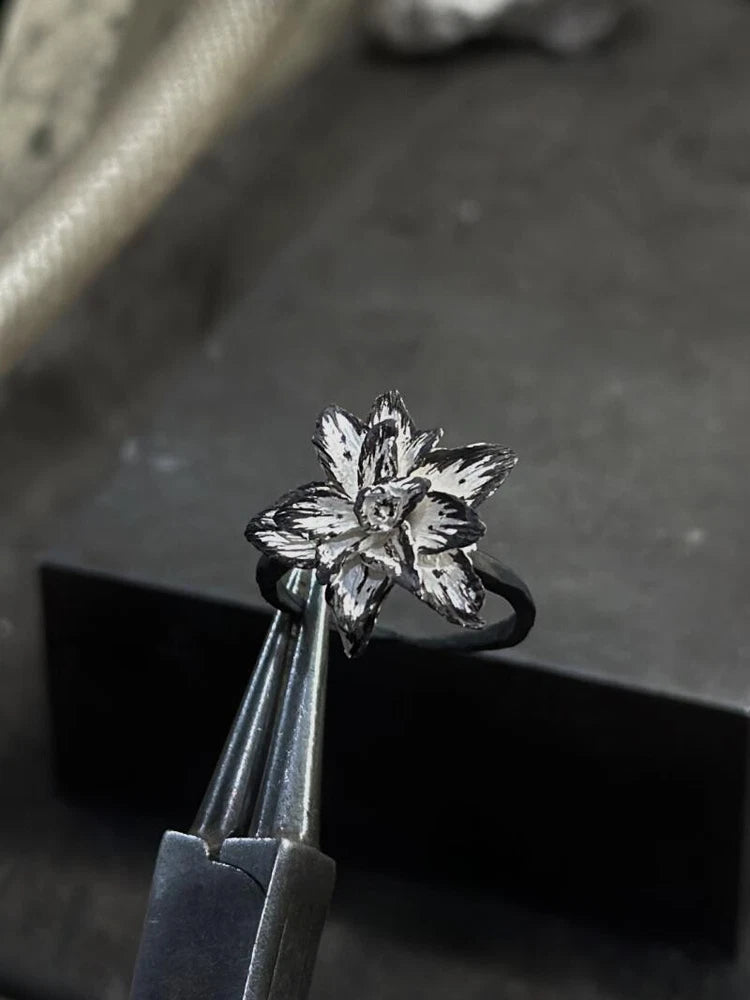 Adjustable open band ring with black band and silver lily flower centerpiece