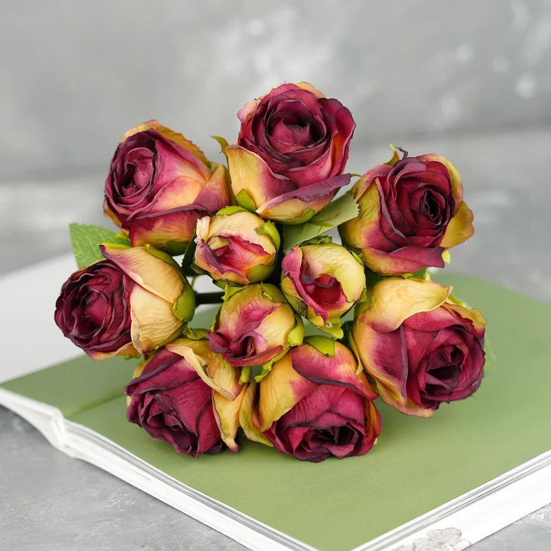 Dried-look artificial rose bouquet with red-purple blooms and green leaves on stems