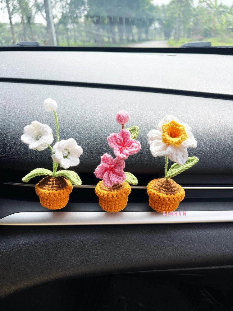 Crochet flower car vent clips with white, pink, and yellow blossoms in small wicker pots