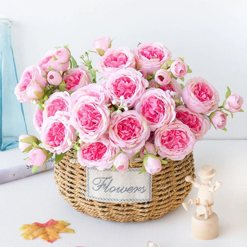 Artificial pink peony flower arrangement in a woven rope basket with faux leaves