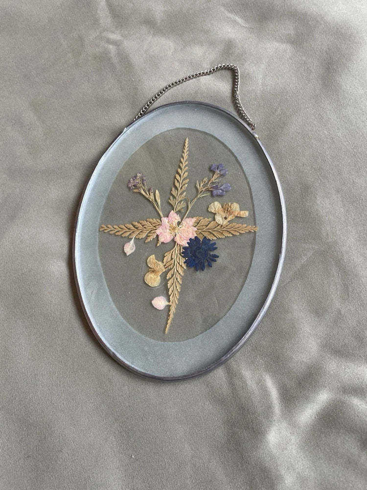 Oval dried flower window hanger with silver-tone frame and pressed floral bouquet