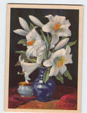 White lily painting on postcard, blue vases with yellow centers, red table cloth.
