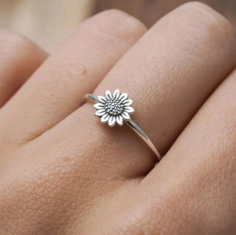 Silver sunflower flower stack ring with detailed center, worn on finger
