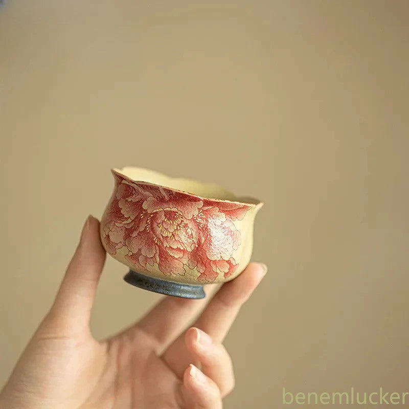 Ceramic peony tea cup with pink floral design, held by hand, small round shape
