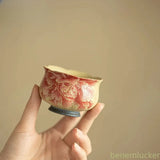 Ceramic peony tea cup with pink floral design, held by hand, small round shape