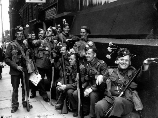 Vintage photo of British soldiers holding flowers, with carnations on their caps