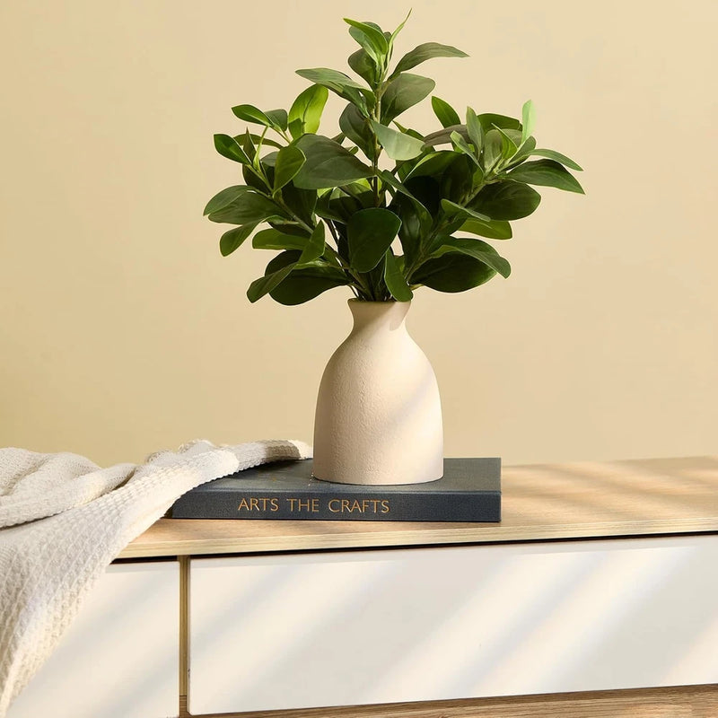 Artificial eucalyptus stems in white pot with green leaves, realistic indoor fake plant
