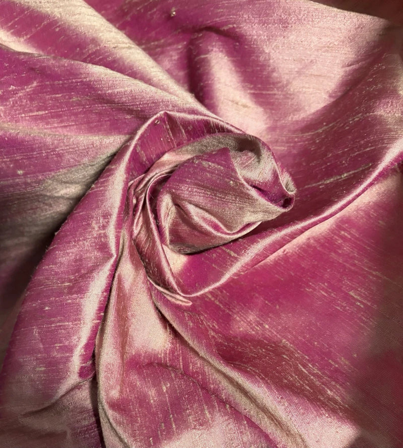 Iridescent dupioni silk fabric, magenta-pink with gold sheen, folded texture