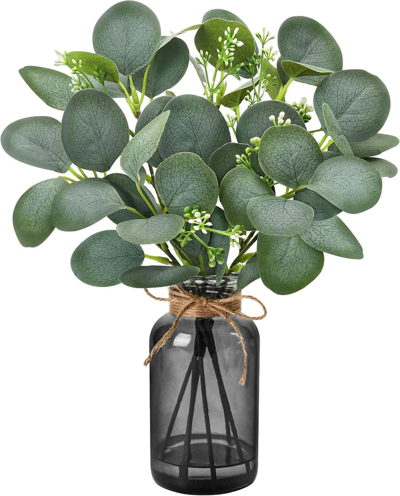 Artificial eucalyptus stems with dark green leaves in a black glass vase with twine