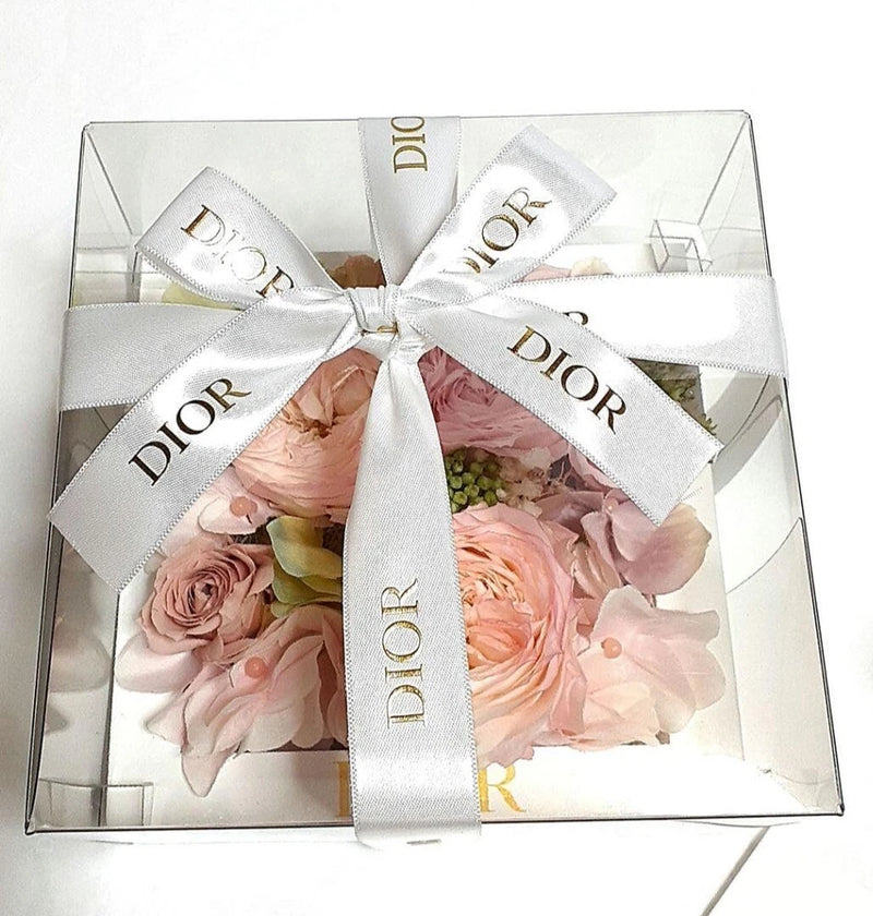 Preserved flower gift box with pink rose-like blooms and white DIOR ribbon bow