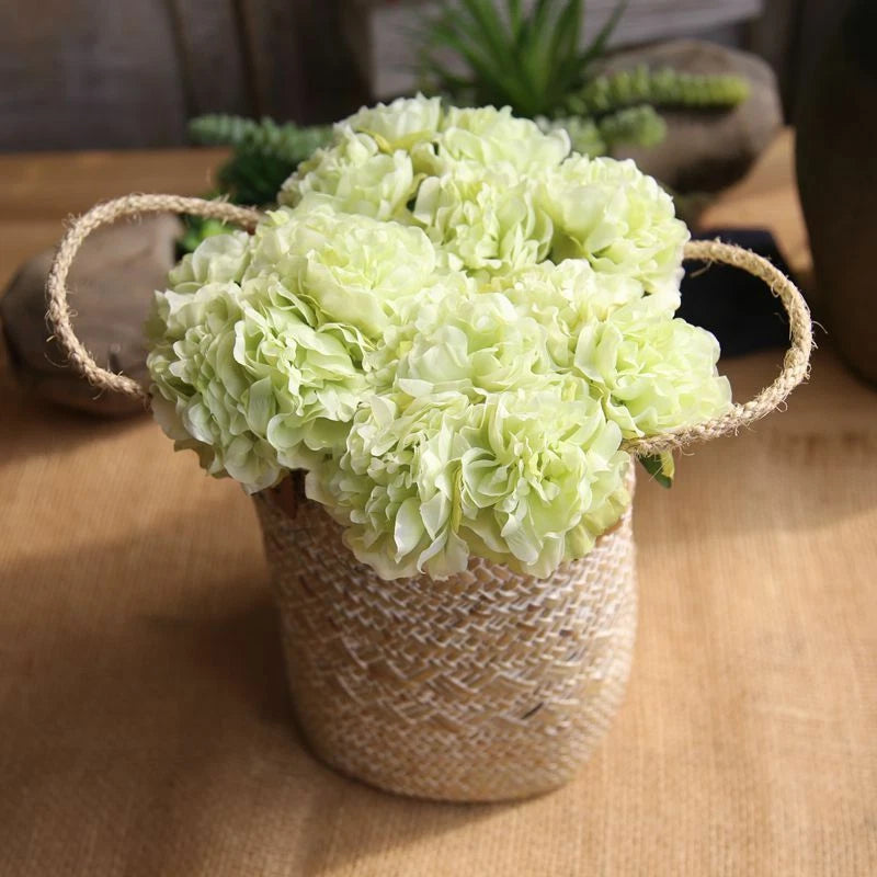 Artificial peony flower bouquet in burlap vase with twine handles, pale green blooms