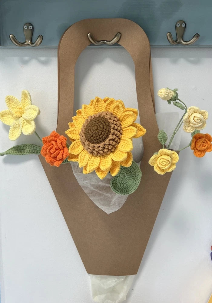 Crochet flower bouquet with yellow sunflower, orange roses, cream blooms, and green leaves